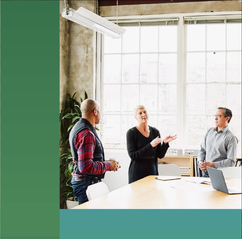 Three office employees hold a discussion in a conference room.