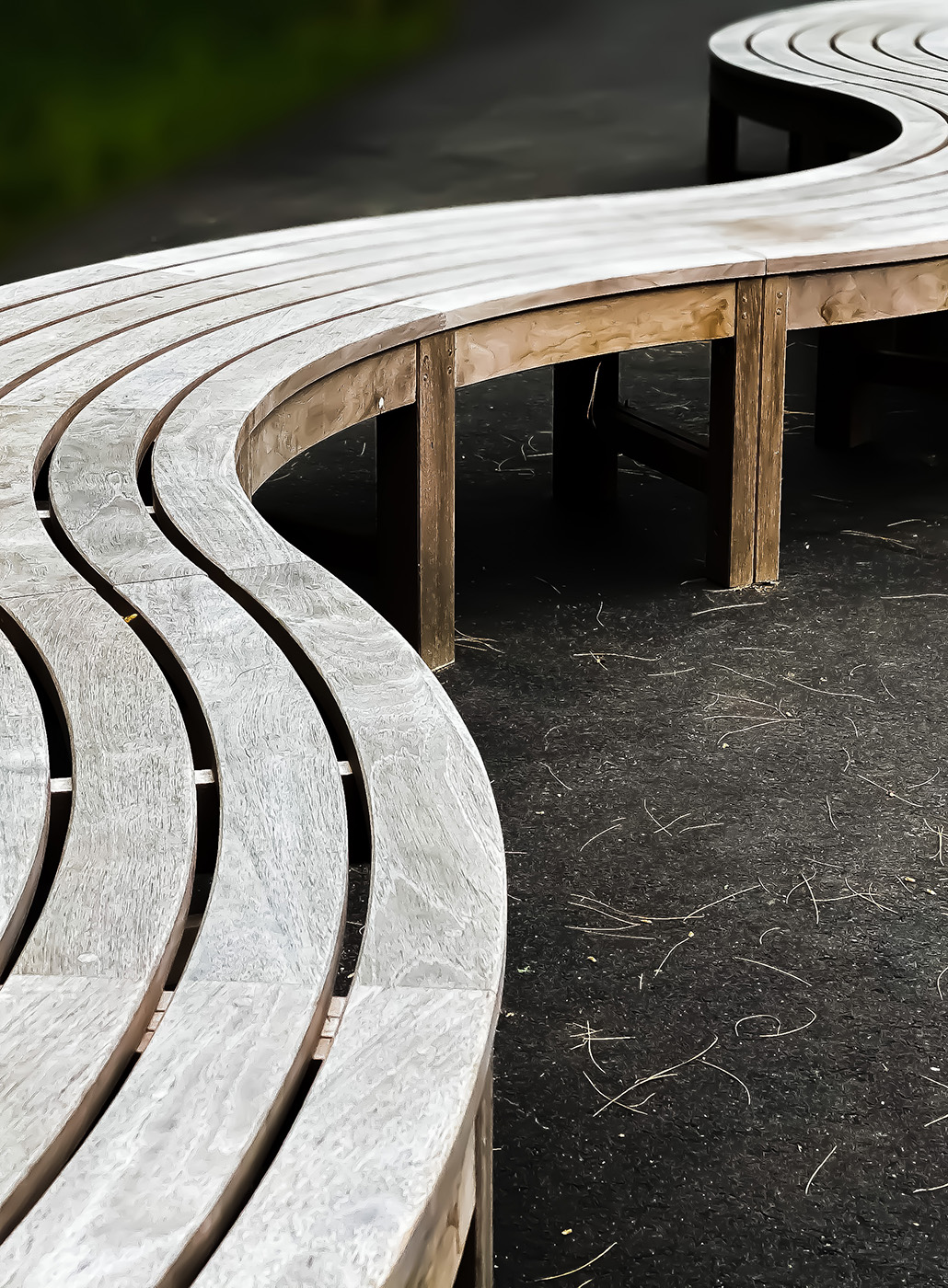 Panchina in legno ondulata su terriccio appena posato in un parco. 