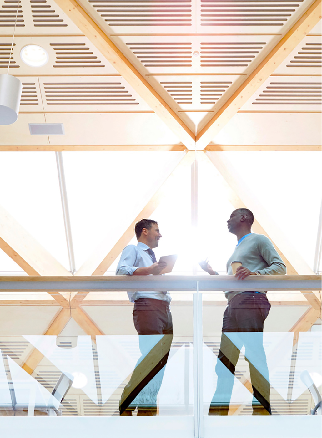 Photo en contre-plongée de deux hommes d’affaires parlant sur un balcon dans une entreprise.